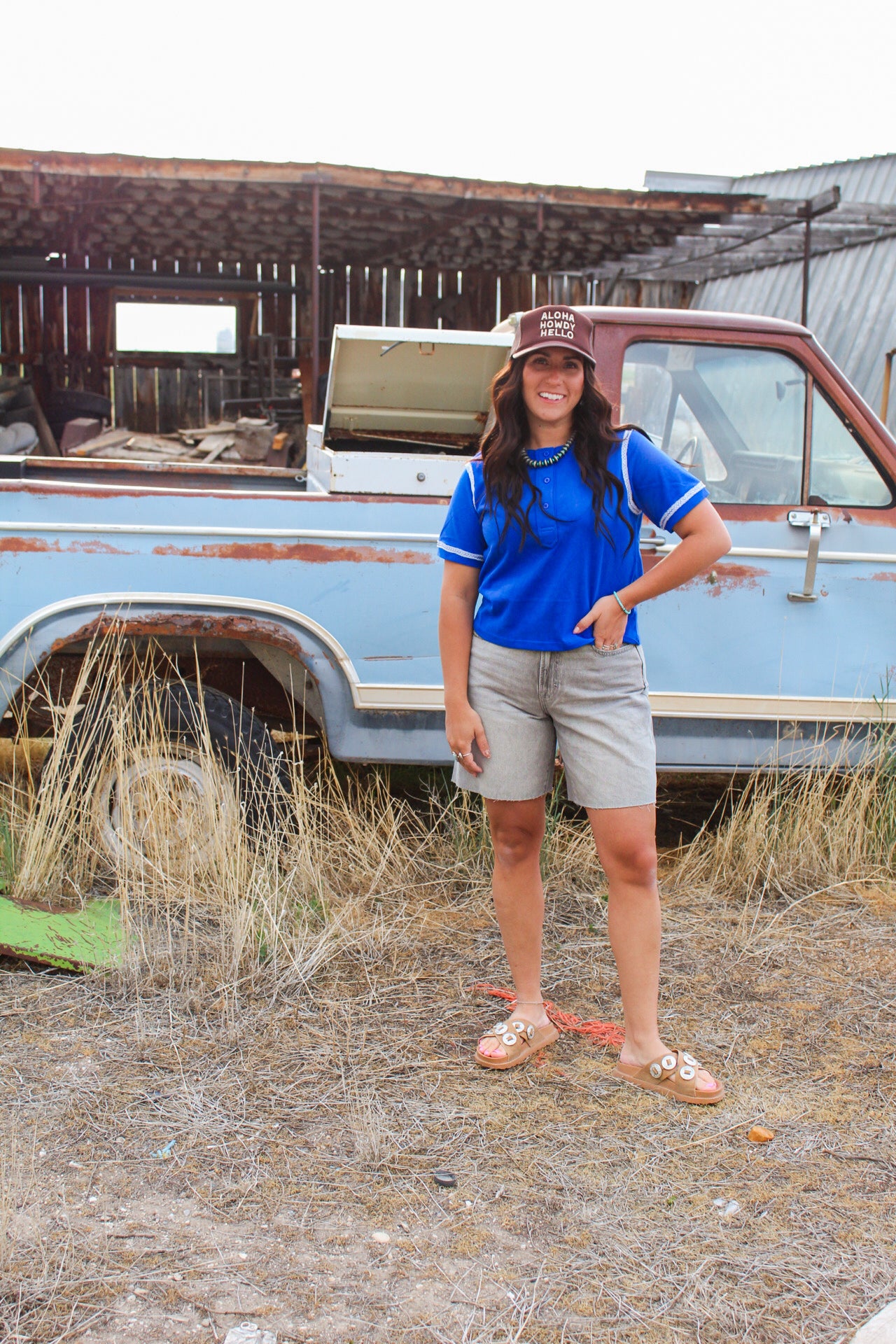 Woman standing in front of an old truck in a desert-like setting