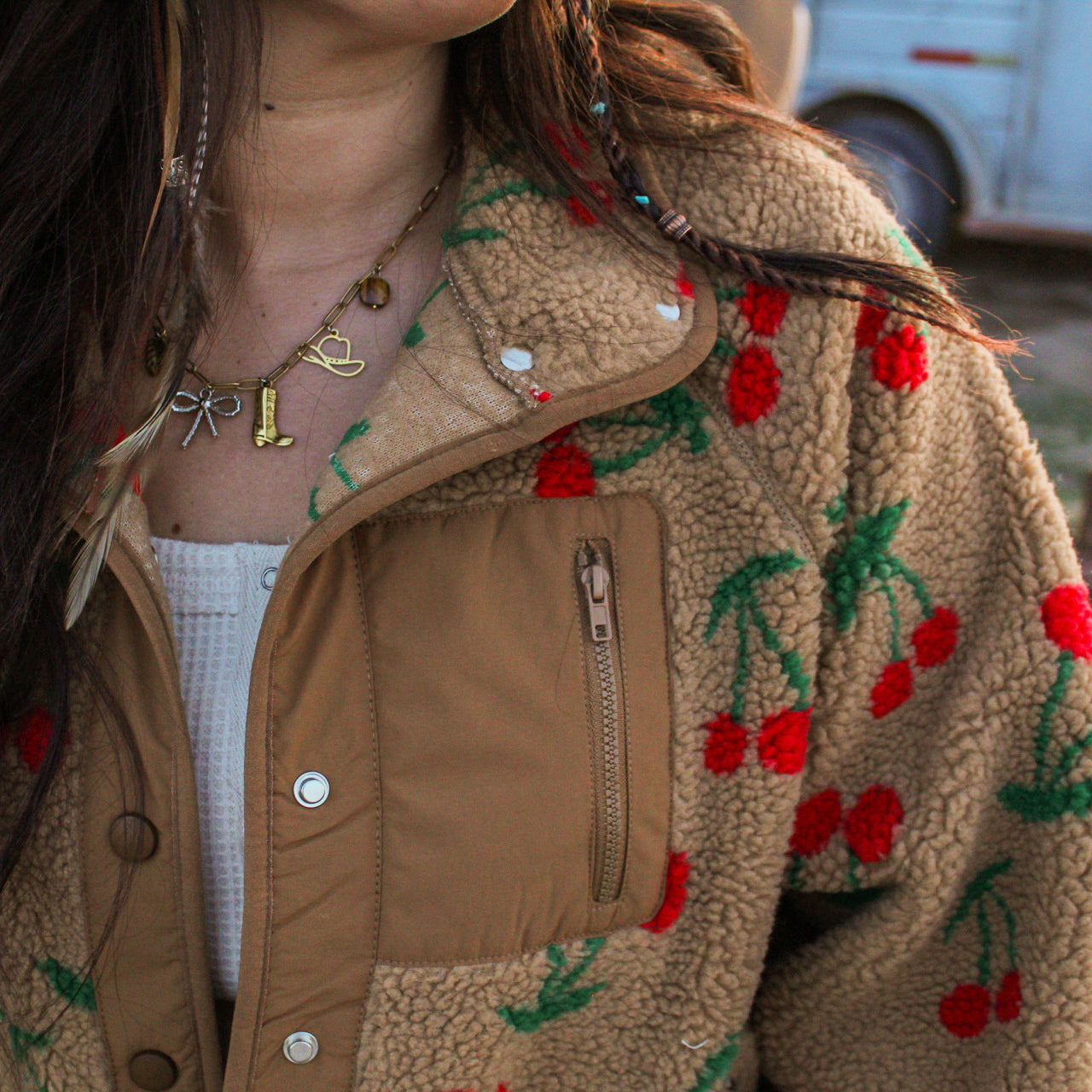 Close-up of a person wearing a brown fleece jacket with cherry patterns.